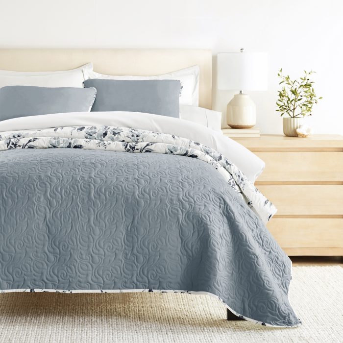 Elegant bedroom with gray quilt and floral accents.