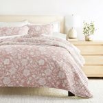 Floral quilt on bed with nightstand decor.