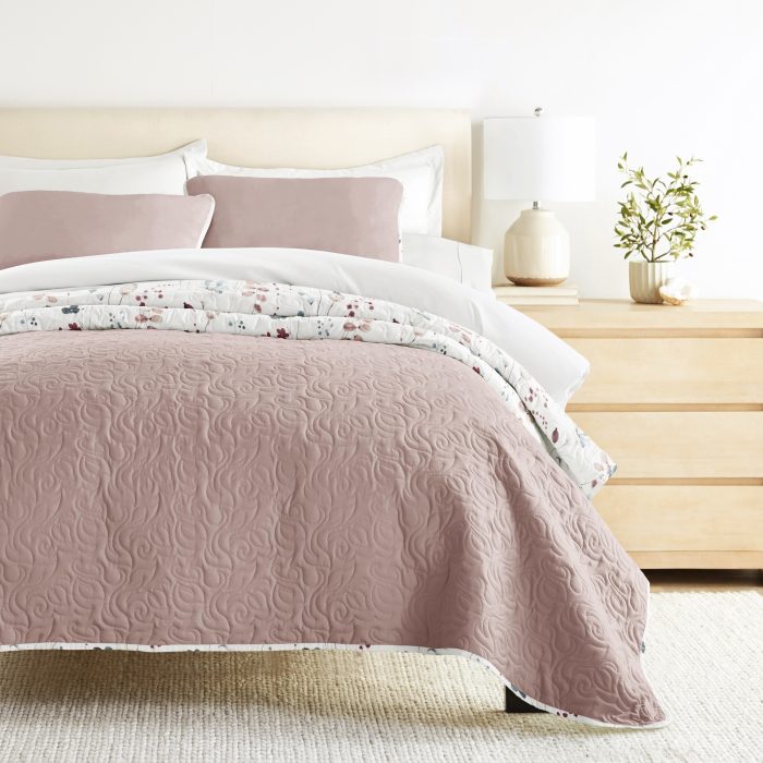 Pink quilted bedding on modern bed with nightstand.