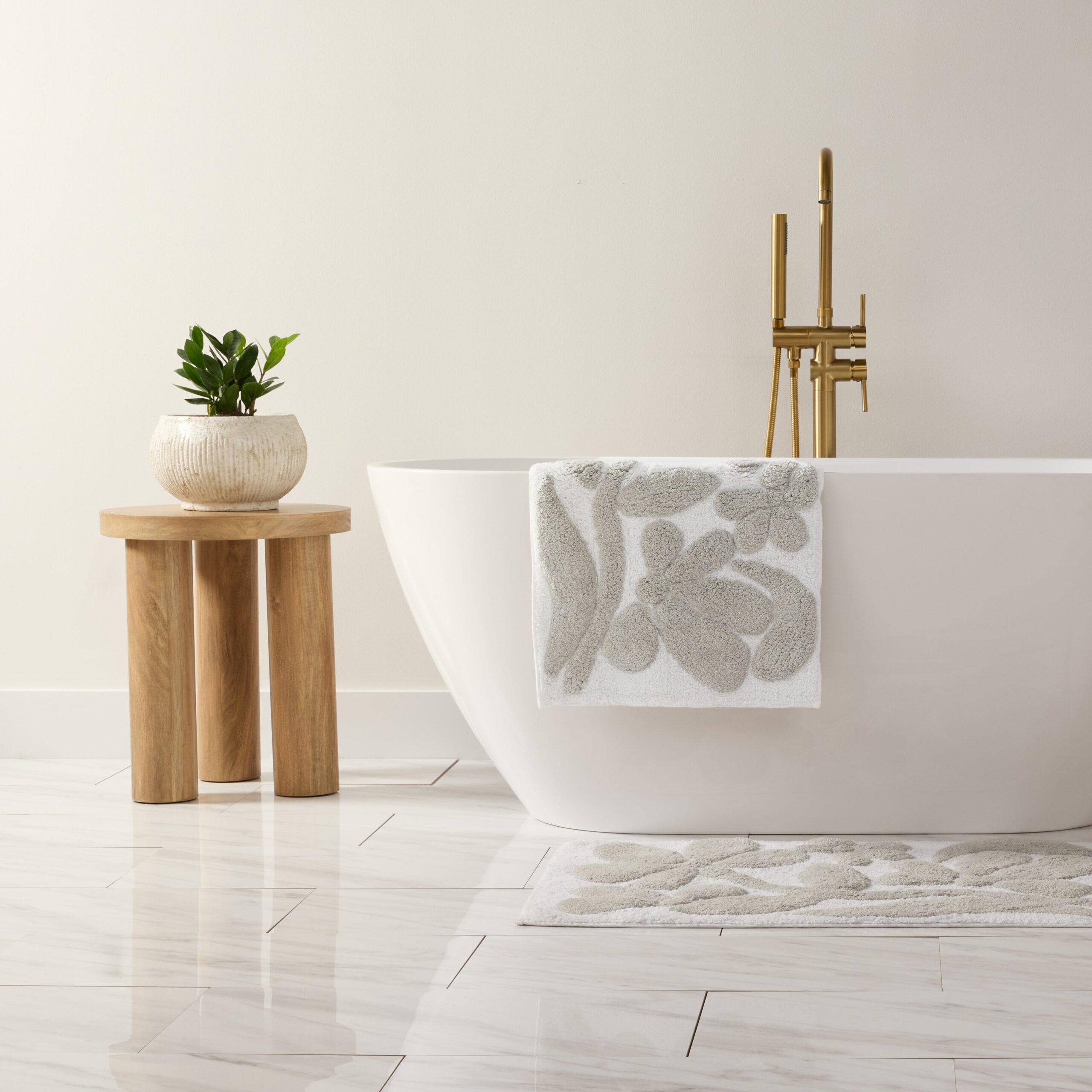 bm-flo-lgray-01-c5-graphic.jpg Modern bathroom with tub, plant, and stylish decor.